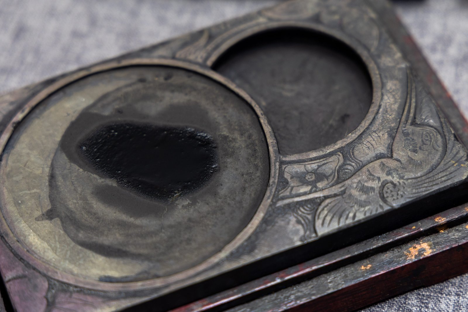 A close-up of a slate inkstone with decorative carved surround