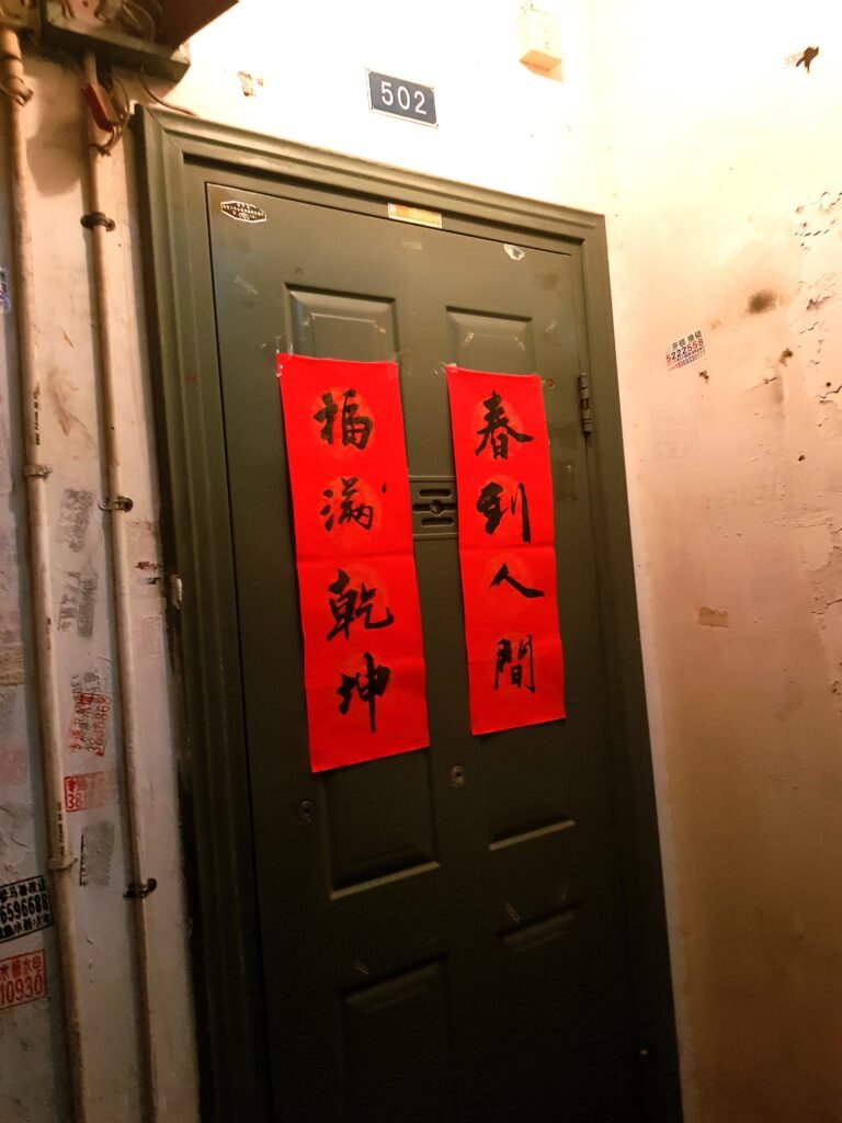 A dark metal door with two vertical red banners with Chinese script attached to the door