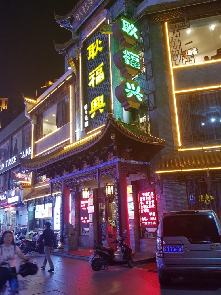 A traditional-style restaurant frontage in Wuhu, China, colourfully lit up against the night sky