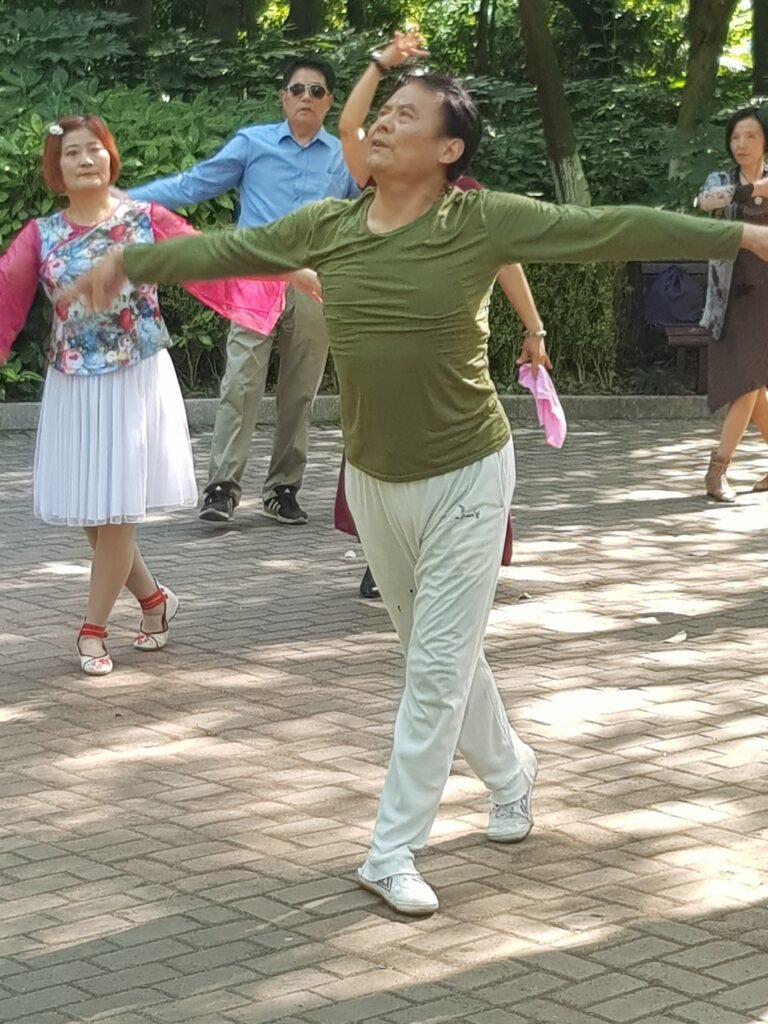 The dancing instructor in Wuhu Park, China, striking a balletic pose with his students observing