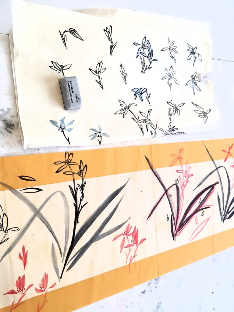 Painted papers attached to a whiteboard with orchid sketches in ink