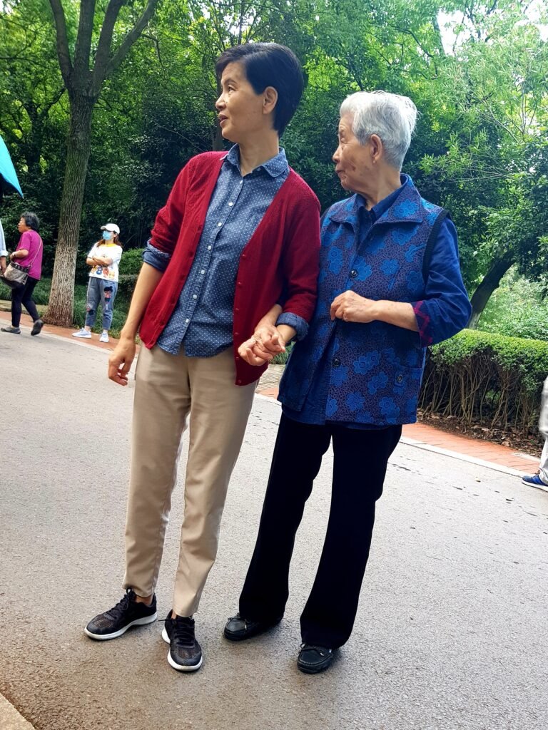 A mother and daughter holding hands in a park as they watch a dancing group