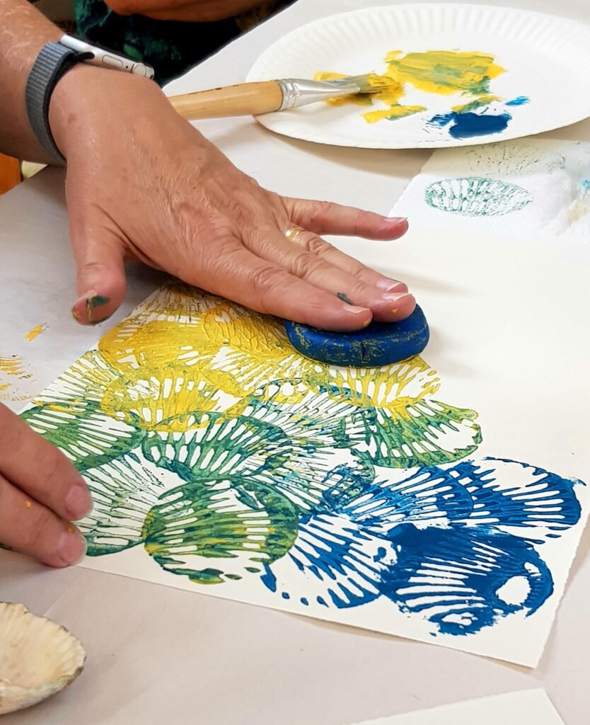 Art workshop in progress, a hand printing shell patterns with plasticine onto paper